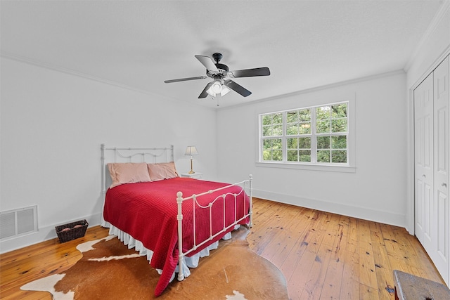 bedroom featuring visible vents, crown molding, baseboards, hardwood / wood-style floors, and a closet