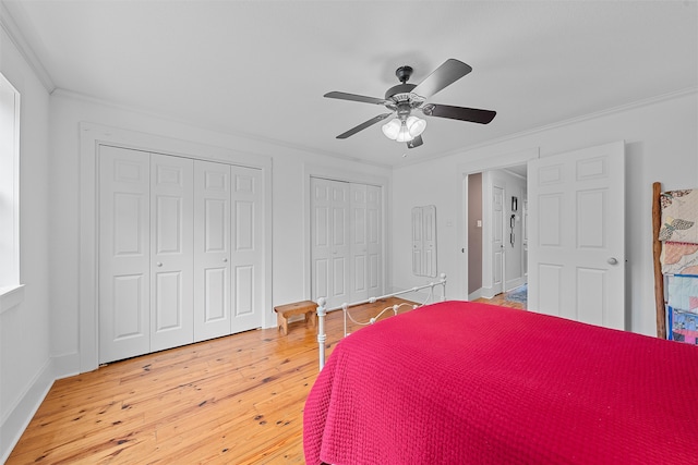 bedroom featuring wood-type flooring, two closets, ceiling fan, and crown molding