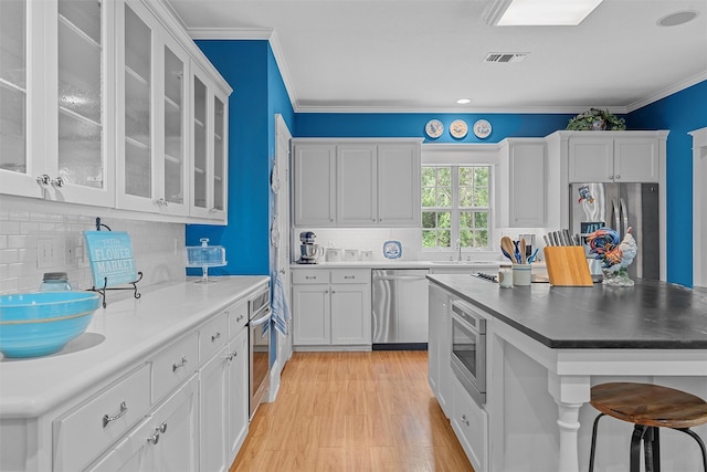 kitchen with visible vents, white cabinets, stainless steel appliances, and ornamental molding