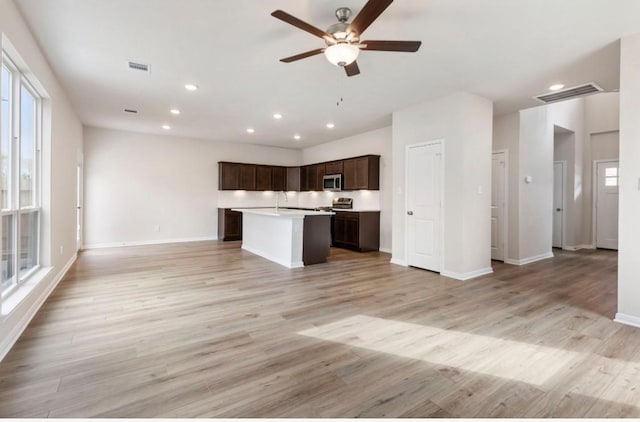 kitchen featuring ceiling fan, a kitchen island, dark brown cabinets, and light hardwood / wood-style flooring