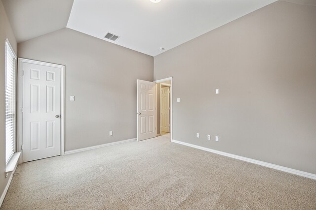 unfurnished bedroom featuring light carpet and vaulted ceiling