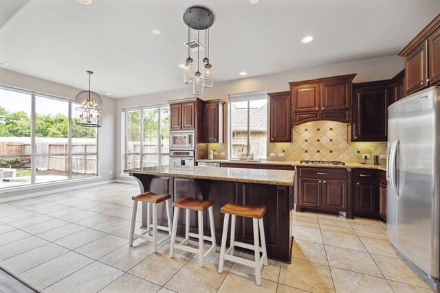 kitchen with pendant lighting, decorative backsplash, a center island, and appliances with stainless steel finishes