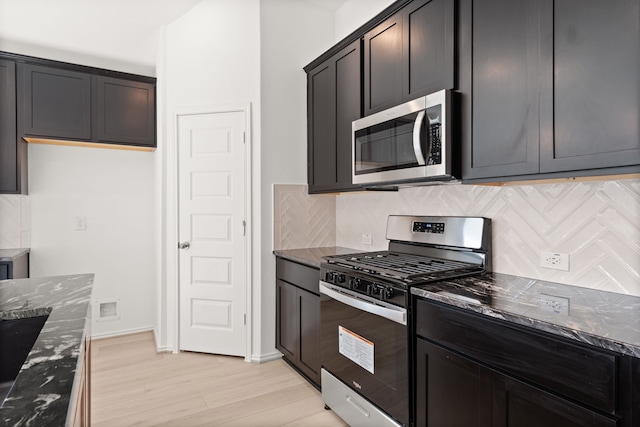 kitchen with backsplash, stainless steel appliances, and dark stone countertops