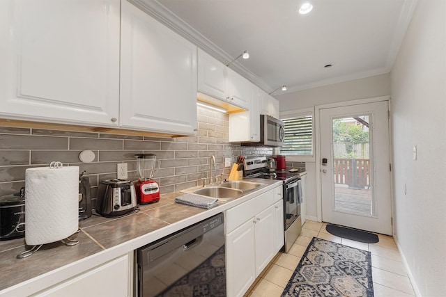 kitchen featuring white cabinetry, tile counters, decorative backsplash, appliances with stainless steel finishes, and ornamental molding