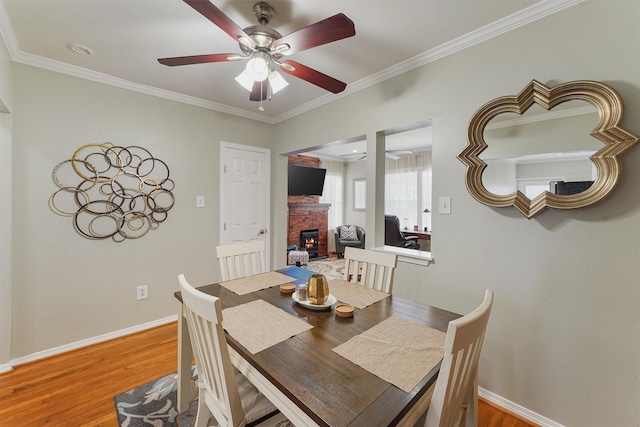 dining area featuring ornamental molding, wood-type flooring, and a brick fireplace