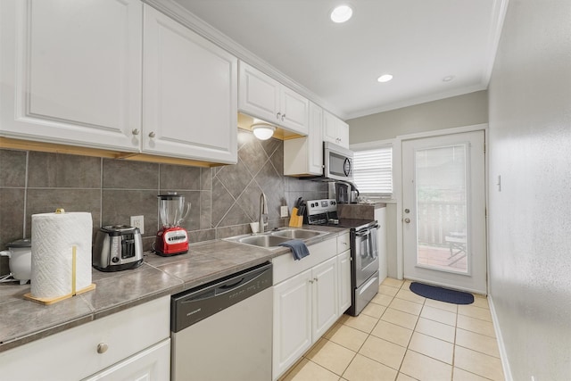 kitchen featuring light tile patterned flooring, appliances with stainless steel finishes, white cabinetry, and sink