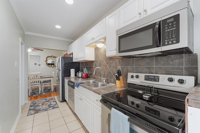 kitchen featuring light tile patterned floors, white cabinetry, sink, and appliances with stainless steel finishes