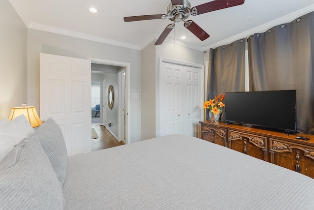 bedroom featuring hardwood / wood-style floors, a closet, ceiling fan, and ornamental molding