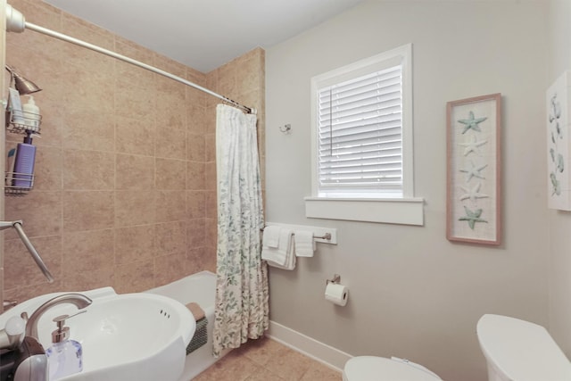 full bathroom with tile patterned floors, shower / bath combo with shower curtain, sink, and toilet