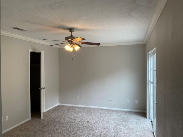 empty room with a textured ceiling, ceiling fan, ornamental molding, and carpet floors