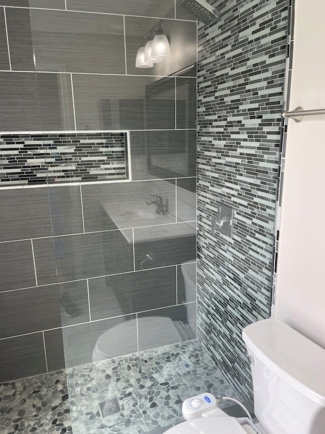 bathroom featuring a tile shower and toilet