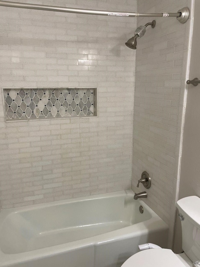 bathroom featuring tiled shower / bath and toilet