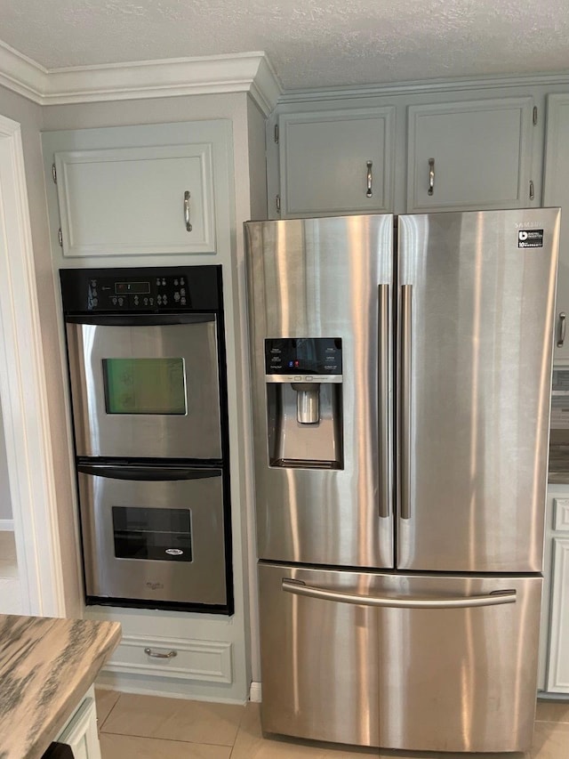 kitchen with crown molding, light tile patterned flooring, stainless steel appliances, and a textured ceiling