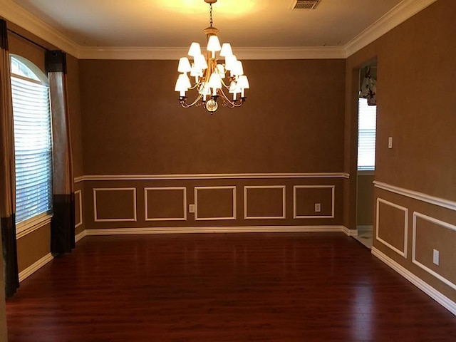 empty room with dark hardwood / wood-style flooring, ornamental molding, and an inviting chandelier