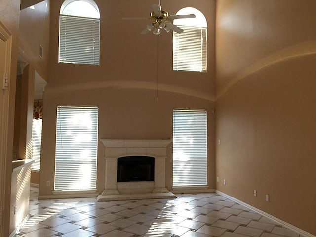 unfurnished living room featuring a high ceiling, ceiling fan, and light tile patterned flooring