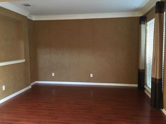 empty room with dark hardwood / wood-style floors and crown molding