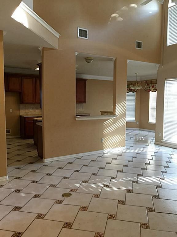 kitchen featuring decorative backsplash, a towering ceiling, and ceiling fan with notable chandelier