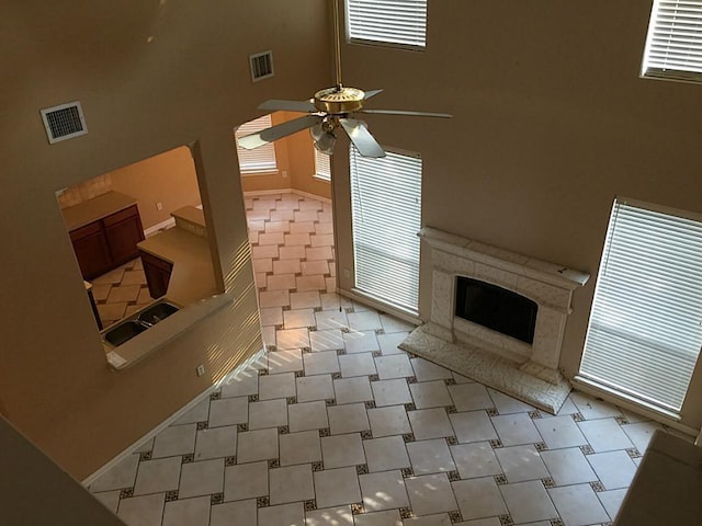 living room with a high ceiling, plenty of natural light, exterior fireplace, and ceiling fan