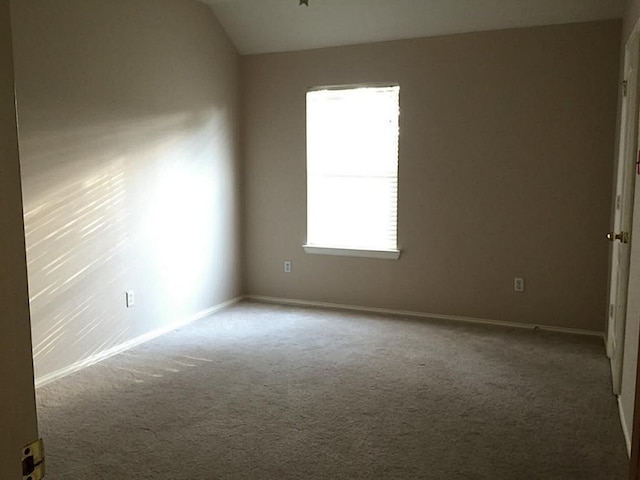 carpeted spare room featuring vaulted ceiling