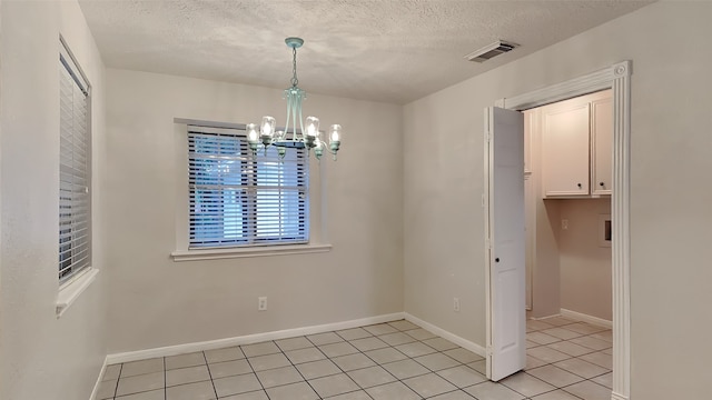 unfurnished dining area with light tile patterned floors, a textured ceiling, and a notable chandelier