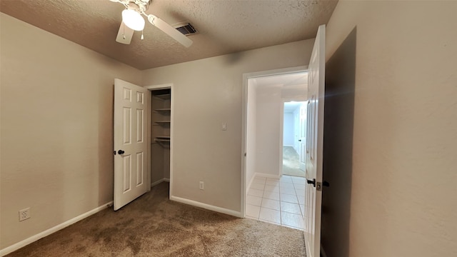 unfurnished bedroom with carpet flooring, ceiling fan, a textured ceiling, a walk in closet, and a closet