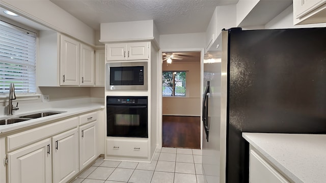 kitchen featuring white cabinets, built in microwave, black oven, light tile patterned flooring, and stainless steel refrigerator