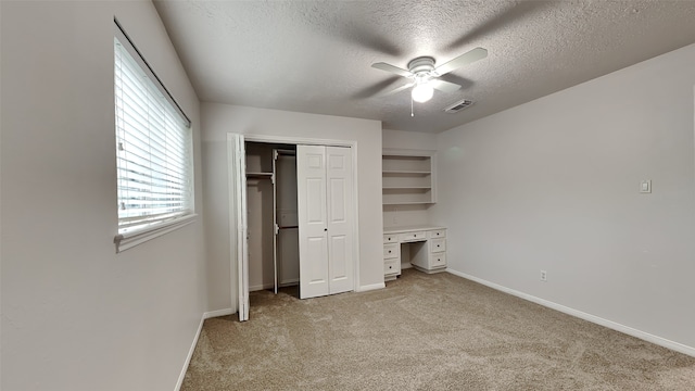 unfurnished bedroom with ceiling fan, a closet, light carpet, and a textured ceiling