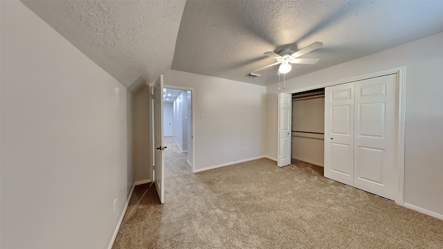 unfurnished bedroom with ceiling fan, lofted ceiling, a textured ceiling, light carpet, and a closet