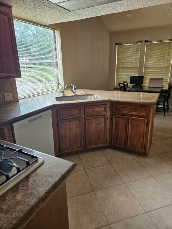 kitchen with kitchen peninsula, gas cooktop, sink, dishwasher, and light tile floors