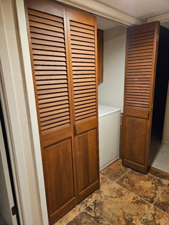 laundry area featuring a textured ceiling, washer / dryer, and dark tile floors