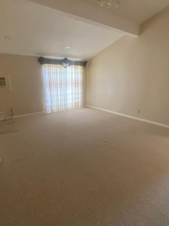 spare room featuring vaulted ceiling with beams and carpet