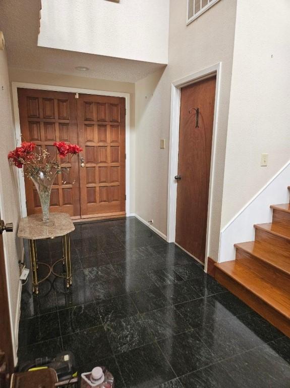 entryway featuring stairway, granite finish floor, visible vents, and baseboards