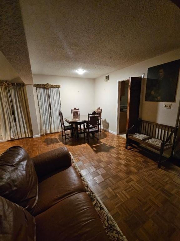 living room with baseboards, visible vents, and a textured ceiling