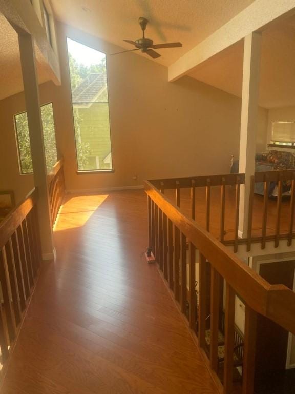 hallway with wood finished floors, beamed ceiling, an upstairs landing, and baseboards