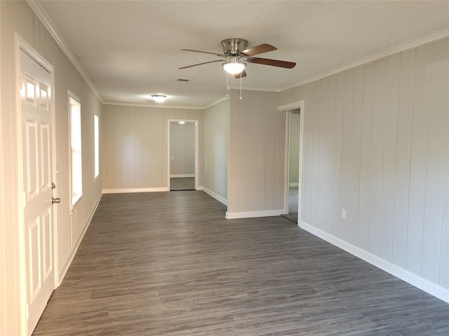 empty room featuring crown molding, wooden walls, ceiling fan, and dark wood-type flooring