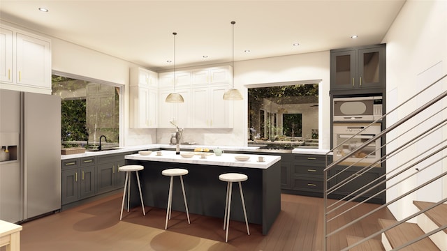 kitchen featuring white cabinetry, sink, a kitchen breakfast bar, stainless steel fridge with ice dispenser, and an island with sink