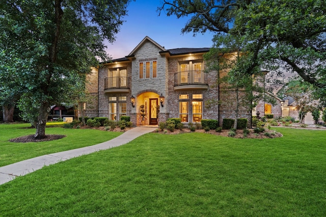 view of front of property with a balcony and a lawn