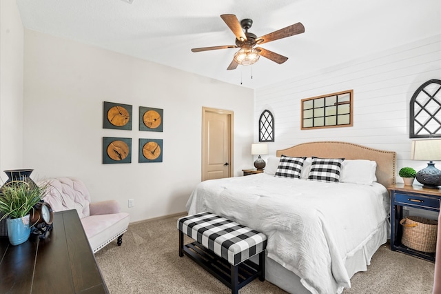 carpeted bedroom featuring ceiling fan and wooden walls