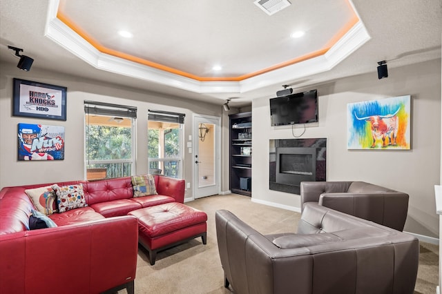 carpeted living room featuring ornamental molding, a fireplace, and a tray ceiling