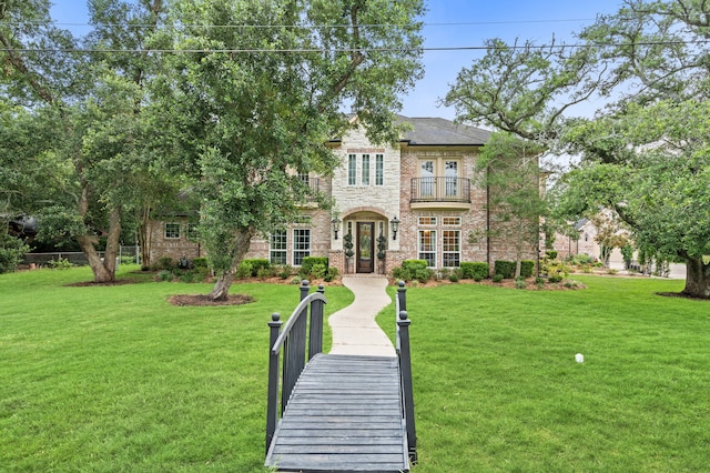 view of front facade featuring a balcony and a front yard