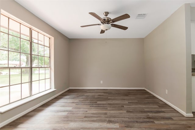 empty room with a wealth of natural light, hardwood / wood-style flooring, and ceiling fan