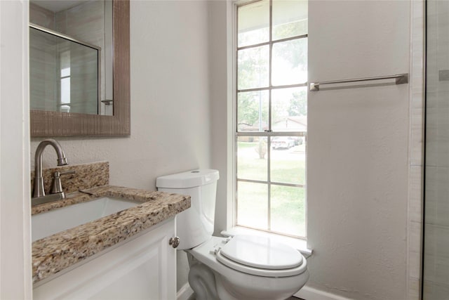 bathroom featuring plenty of natural light, an enclosed shower, toilet, and vanity