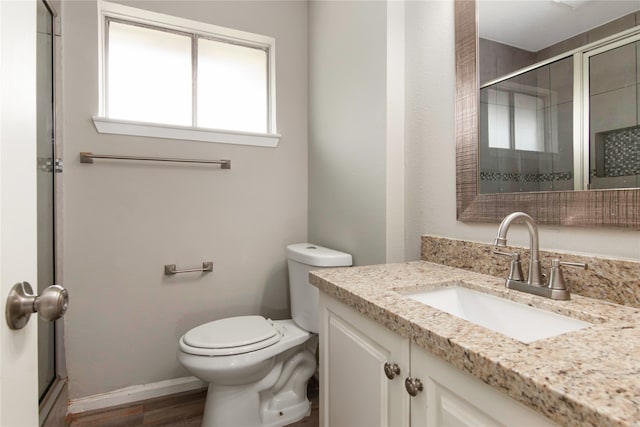 bathroom with hardwood / wood-style flooring, toilet, and vanity with extensive cabinet space