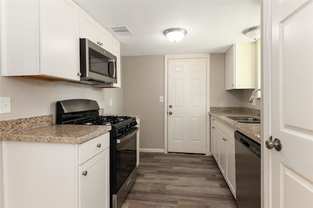 kitchen with stainless steel appliances, white cabinets, dark hardwood / wood-style floors, light stone counters, and sink