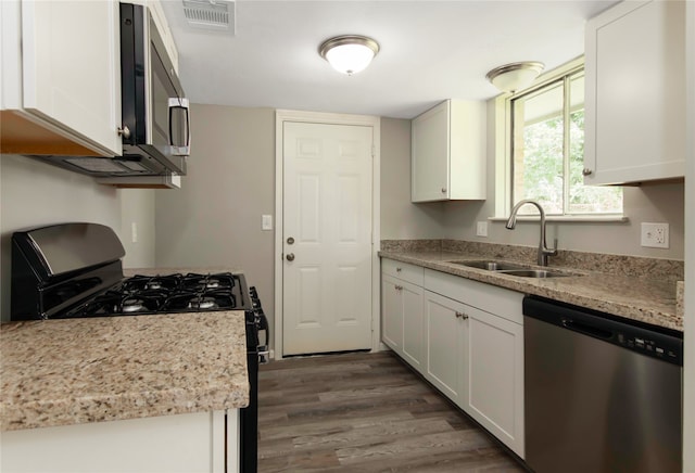 kitchen with light stone counters, dark hardwood / wood-style floors, white cabinets, sink, and appliances with stainless steel finishes