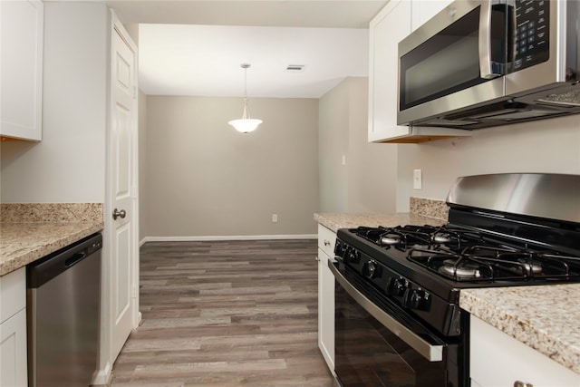 kitchen featuring white cabinetry, stainless steel appliances, light stone counters, wood-type flooring, and pendant lighting