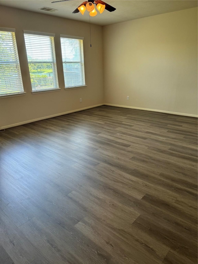 empty room with ceiling fan, a wealth of natural light, and dark hardwood / wood-style floors