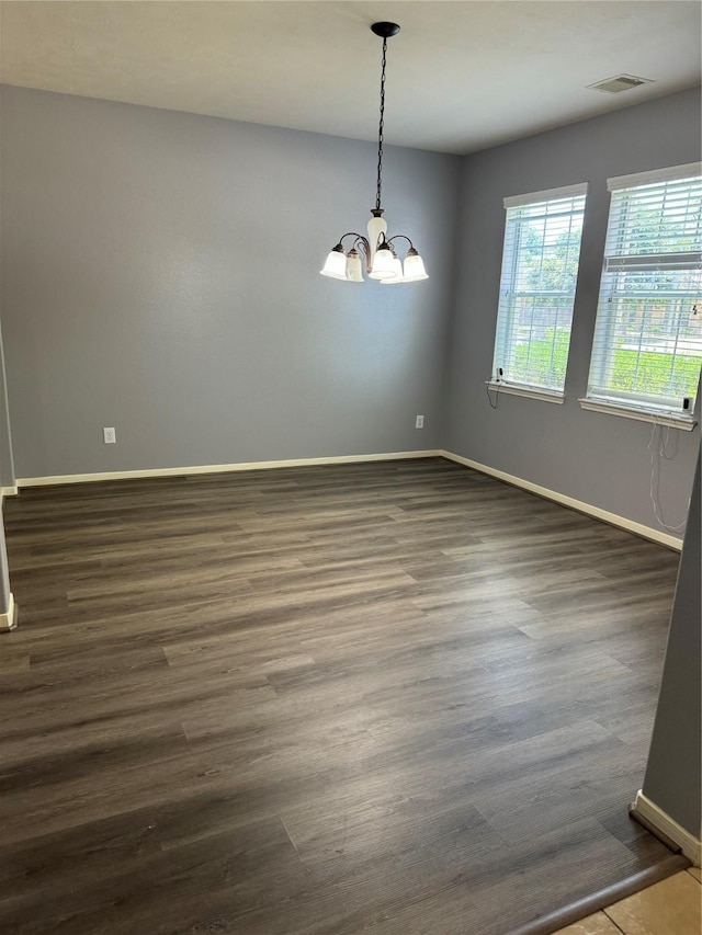 spare room featuring a notable chandelier and dark hardwood / wood-style floors