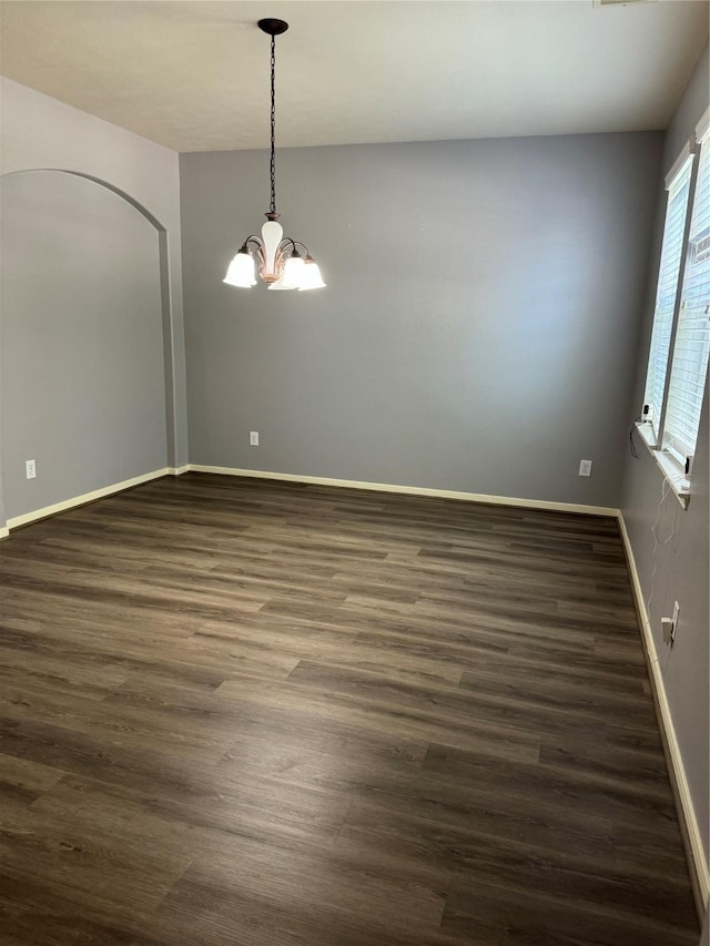 unfurnished room with dark wood-type flooring and a chandelier