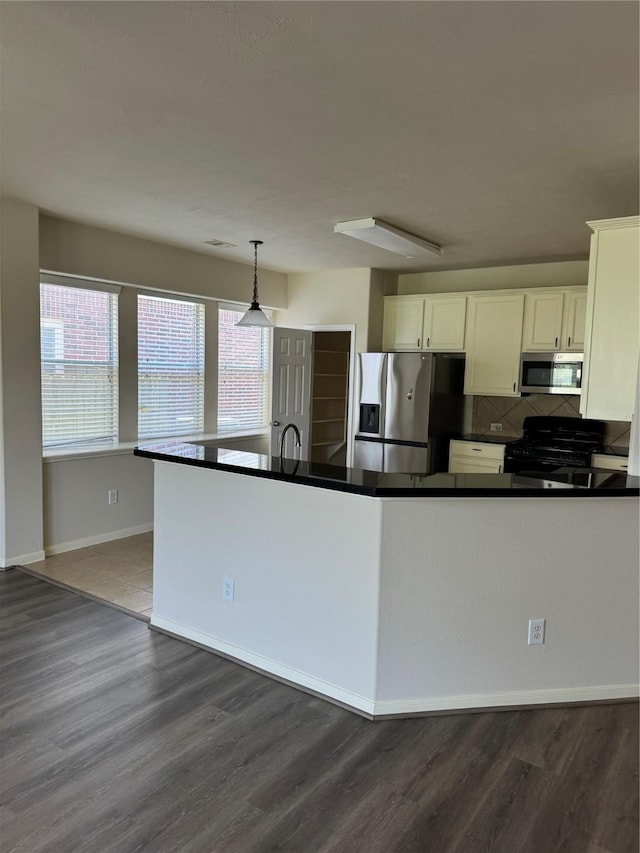 kitchen with white cabinets, appliances with stainless steel finishes, dark wood-type flooring, backsplash, and hanging light fixtures